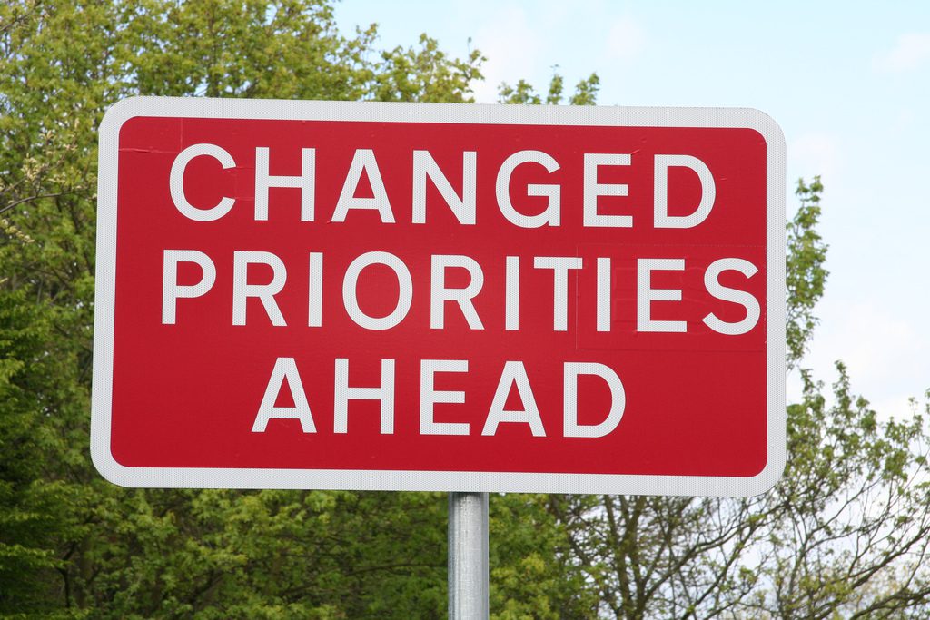 Red sign that reads "Changed Priorities Ahead"