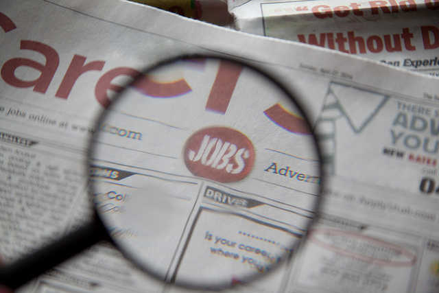 Magnifying glass highlighting the word "Jobs" in a newspaper
